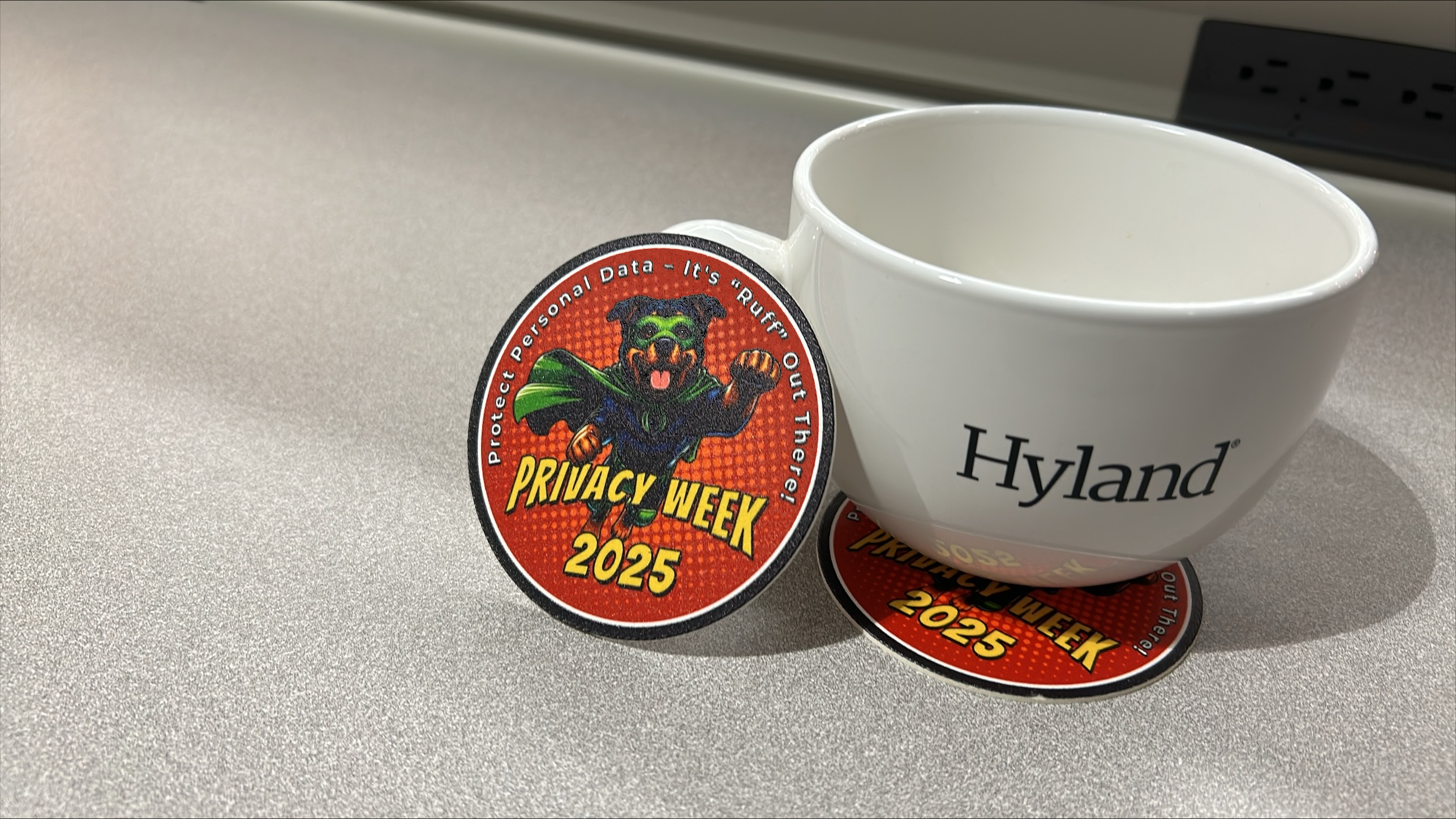 Privacy Week 2025 mascot coasters alongside a Hyland mug
